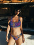Psychedelic animal print bikini top with multicolor tiger pattern in neon pink, purple, orange, and blue, made of stretchy recycled fabric with wide shoulder straps and scoop neckline.
